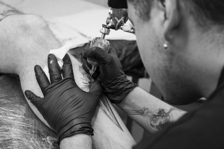 Profesional del tatuaje tatuando a una persona.